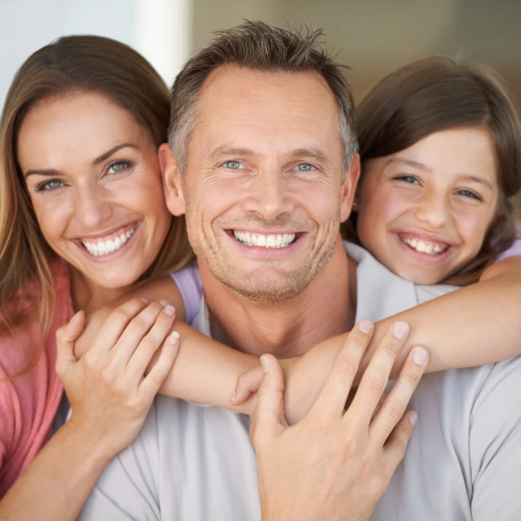 Happy family of three with bright smiles after receiving dental care in Fresno