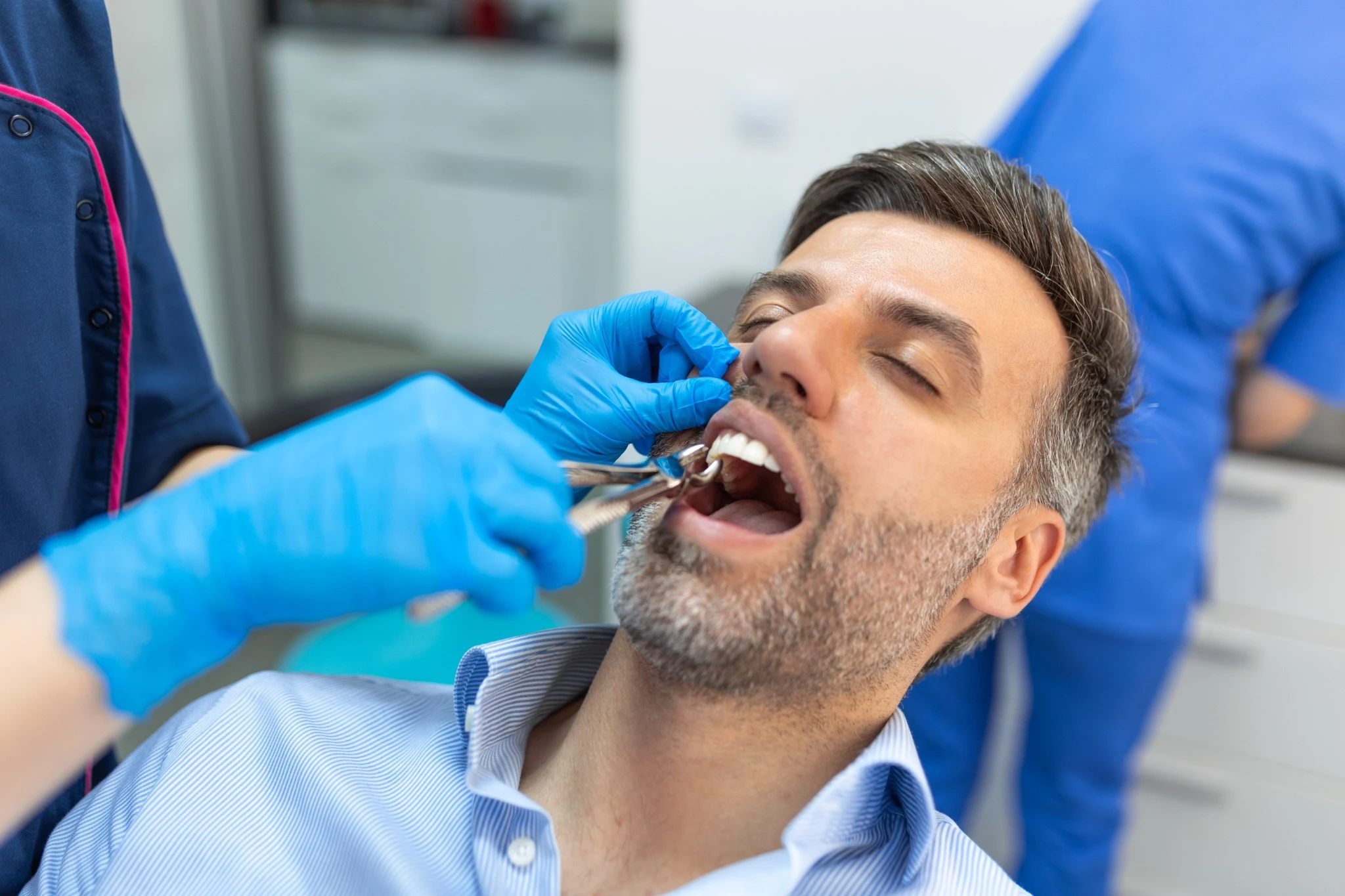 Surgeon performing tooth extraction with forceps